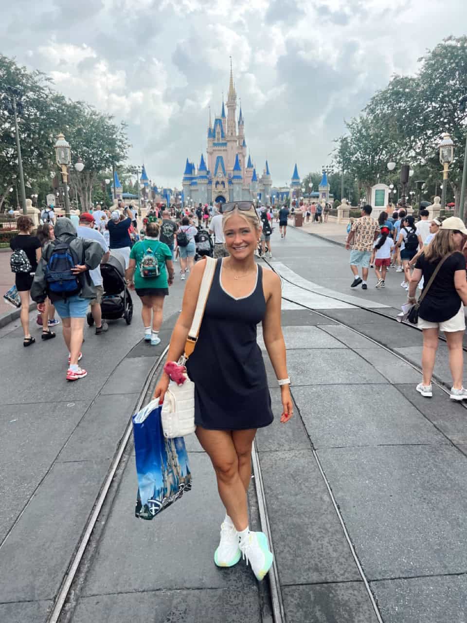 Disney castle at Magic Kingdom, smiling woman enjoying her visit to Disney World.