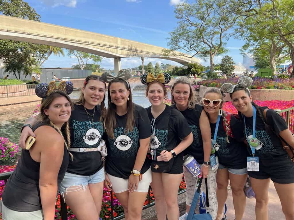 Group of women wearing "407 & Beyond" t-shirts and Minnie Mouse ears hats at Disney park, smiling for the camera.